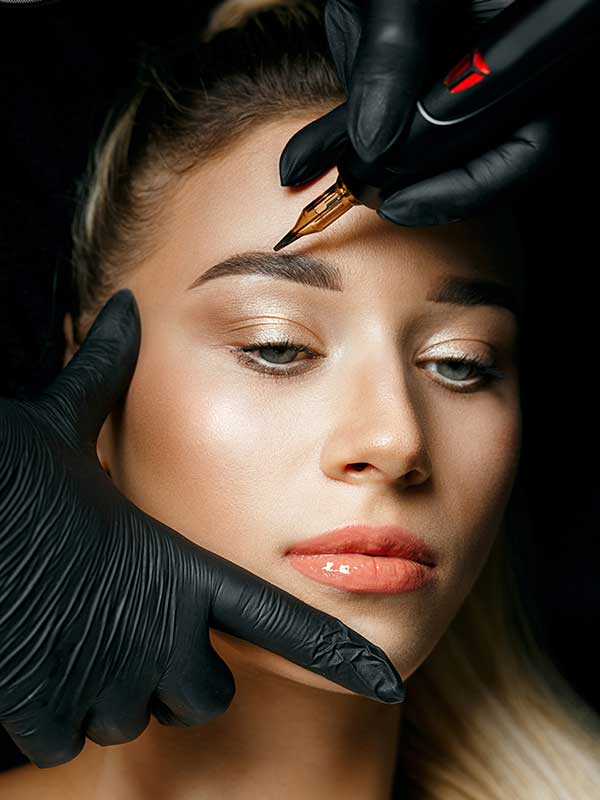 Kosmetikerin in Handschuhen macht Permanent Make-up